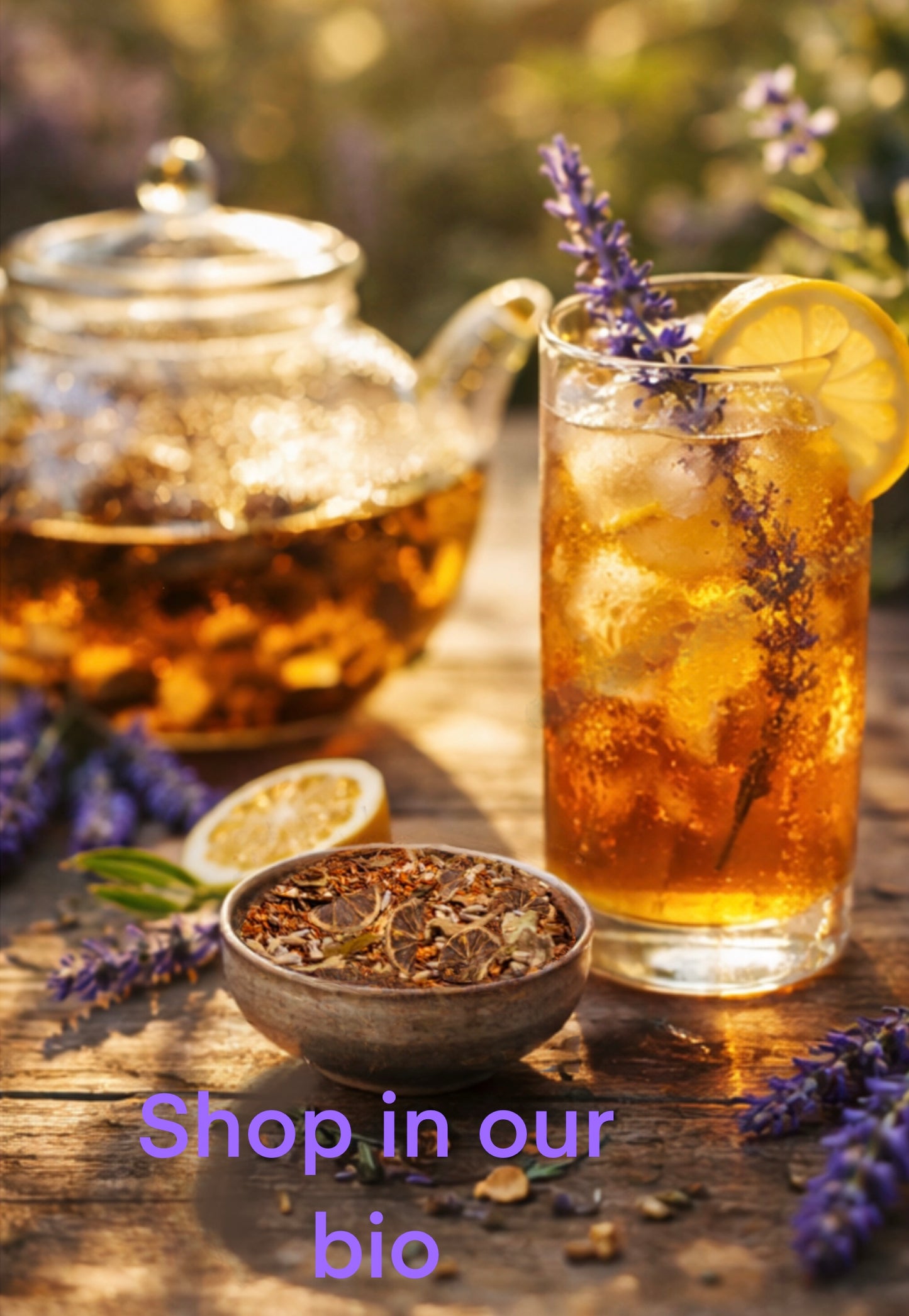 Tea set with a teapot, glass of iced tea with lemon and lavender, and a bowl of loose tea leaves on a wooden surface.