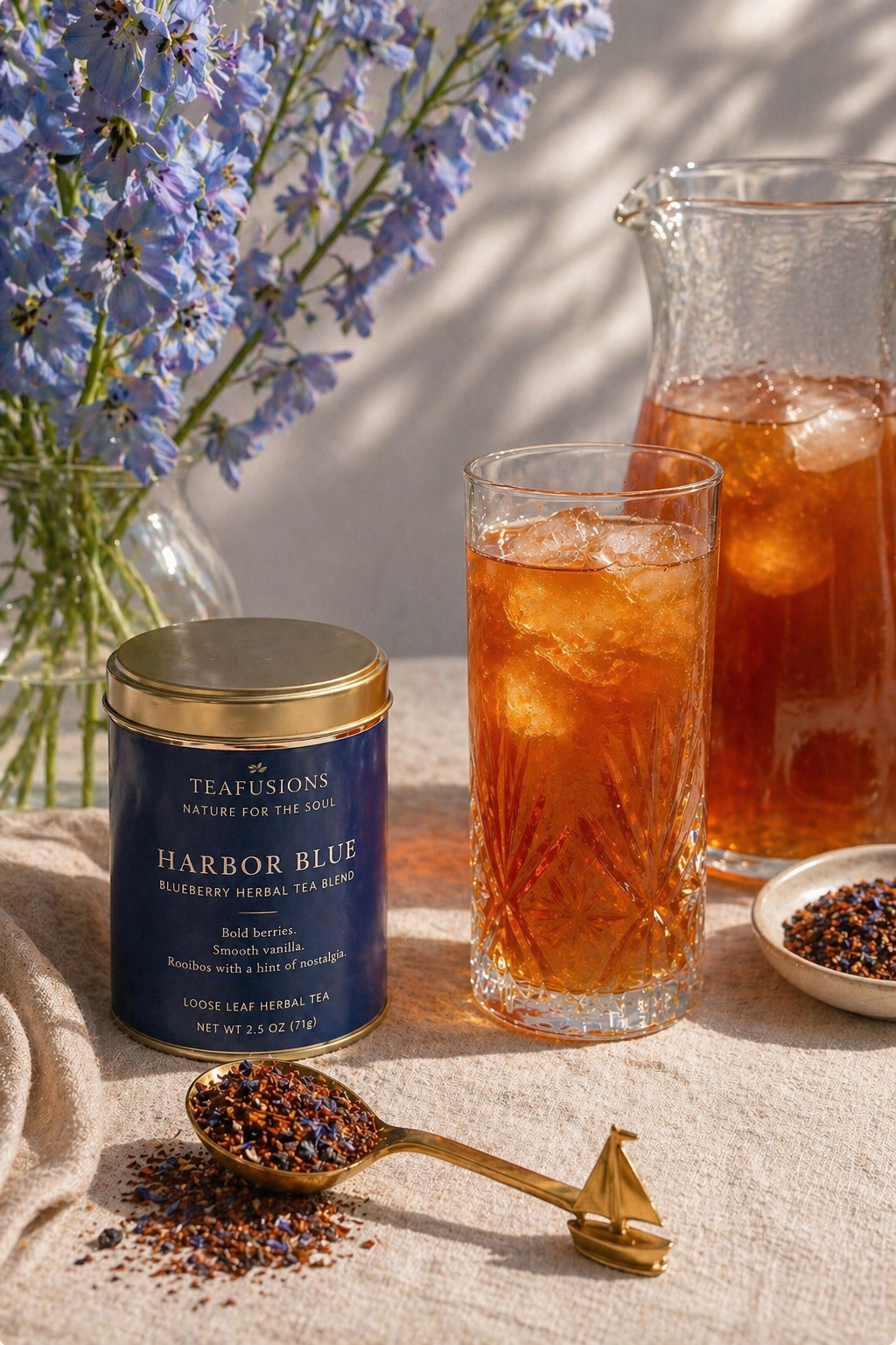 Harbor Blue iced rooibos tea styled with glass pitcher, gold spoon, and blue florals