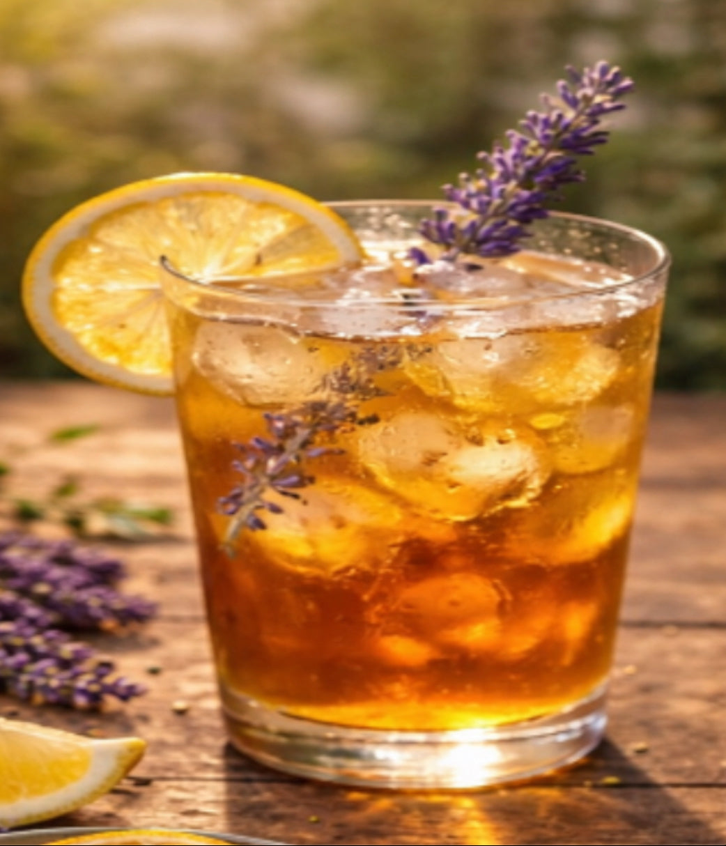 Glass of iced tea with lemon slices and lavender flowers on a wooden surface.