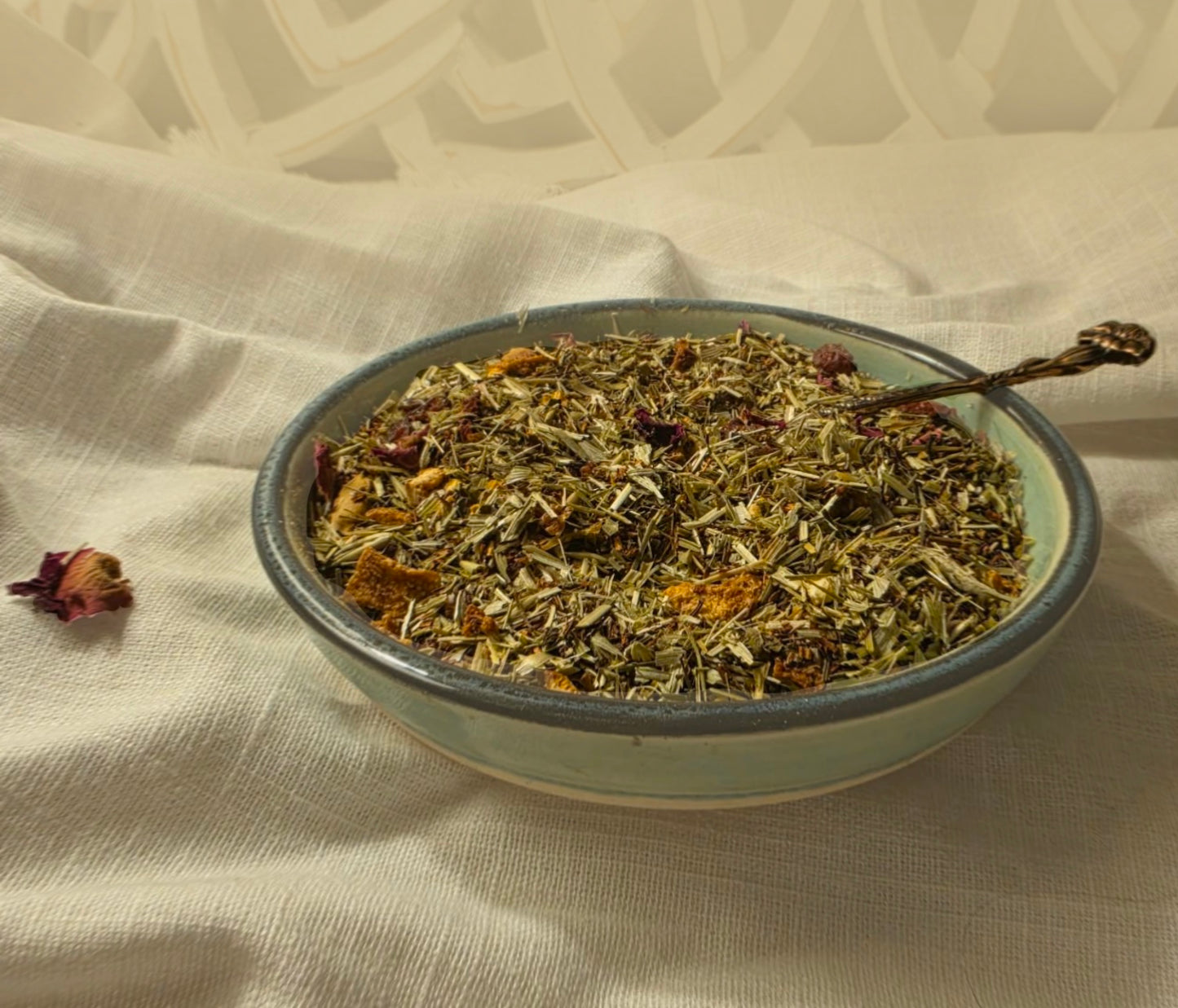 Bowl of dried herbs & fruit with a spoon on a textured fabric background
